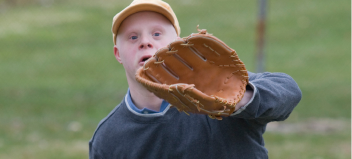 Young man with down syndrome ready to catch baseball with glove. 